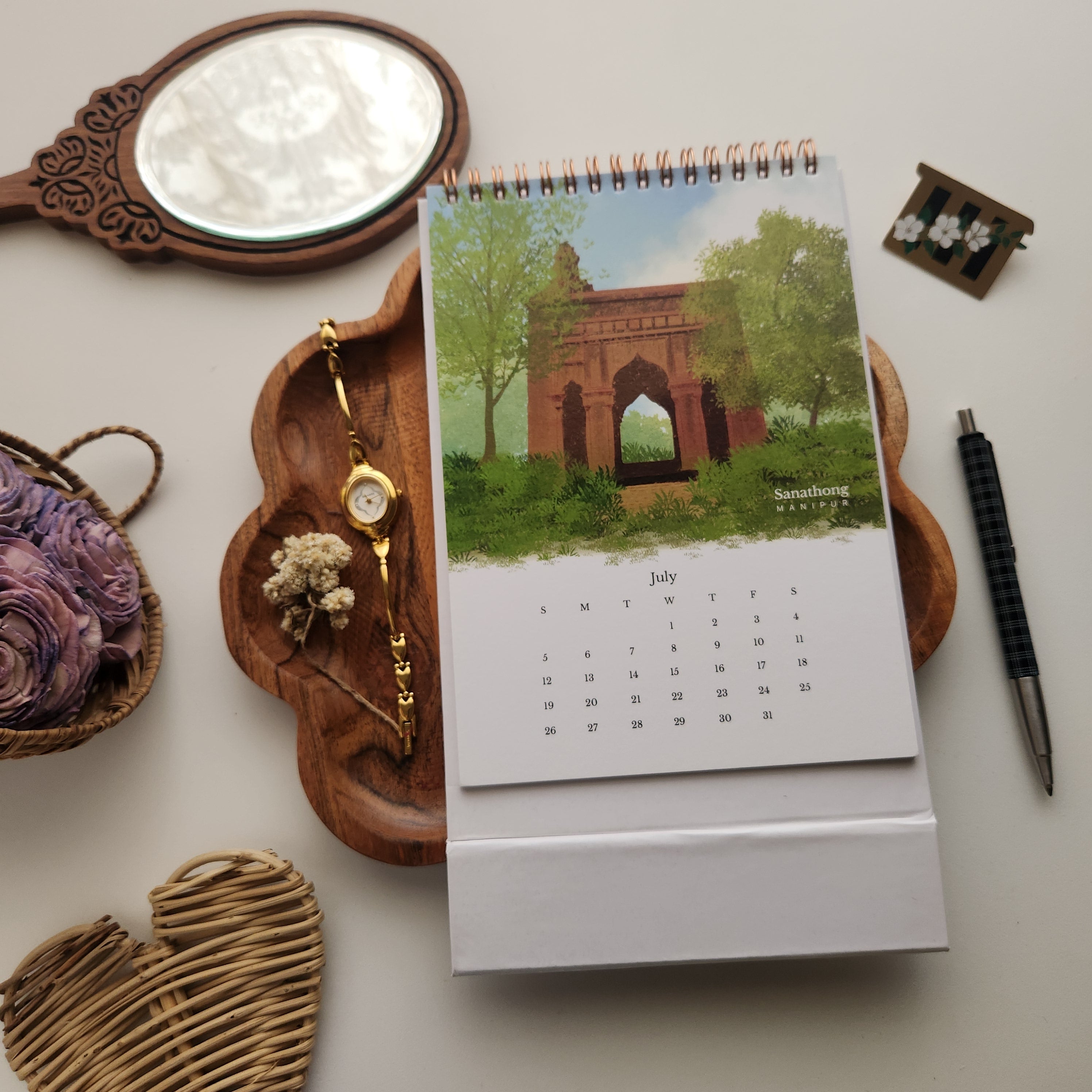 2026 Wonders of Northeast India Calendar open to July with an illustration of Manipur's Sanathong
